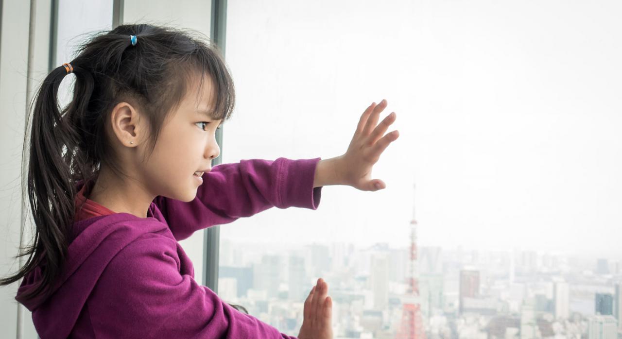 Niña mirando a través de la ventana